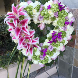 Heart-shaped floral wreath with pink lilies, roses, hydrangeas, and purple orchids