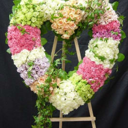 Heart-shaped floral wreath on an easel with pastel roses and hydrangeas