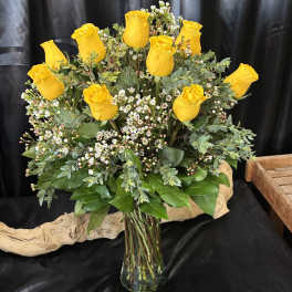 Yellow roses arranged in a clear glass vase with small white filler flowers
