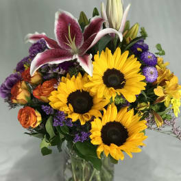 Bouquet of sunflowers, lilies, and roses in a glass vase