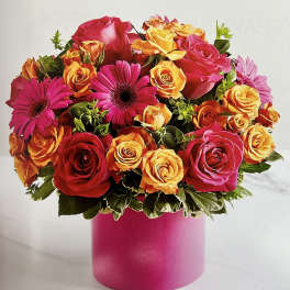 Bouquet of pink, orange, and yellow roses with magenta daisies in a pink vase