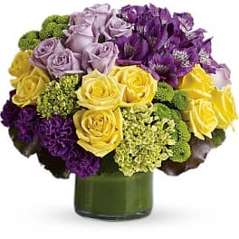 Bouquet of purple, yellow, and lavender flowers in a green vase