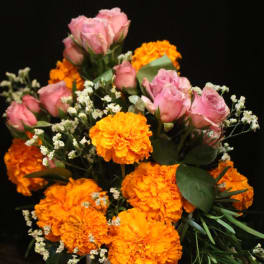 Pink roses and orange marigolds in a white vase