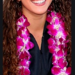 Woman wearing a magenta orchid lei and graduation cap