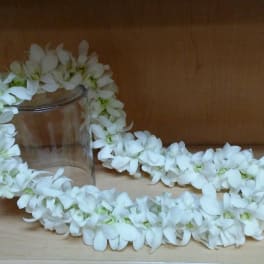 White flower lei draped around a clear glass jar