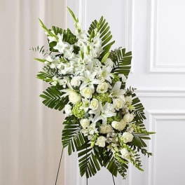 White floral standing spray with lilies and roses on a display easel