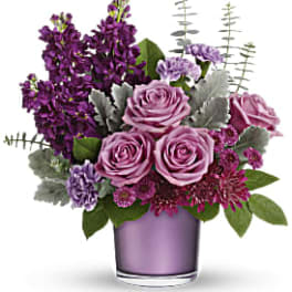 Purple roses and mixed blooms in a lavender glass vase