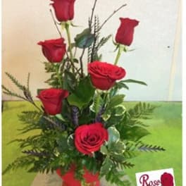 Tall arrangement of red roses in a red container