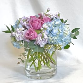 Pink roses and blue hydrangeas in a clear glass vase