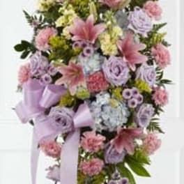 Standing floral spray with pink, lavender, and yellow flowers on a ribboned easel