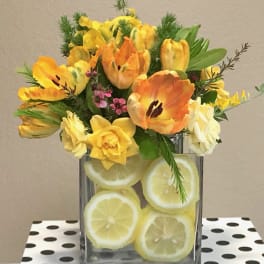 Yellow and orange tulips in a glass vase filled with lemon slices