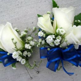 Two white rose corsages with blue ribbon bows