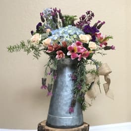 Mixed bouquet in a galvanized pitcher with blue hydrangea and pink flowers