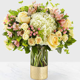 Bouquet of cream and pink flowers in a gold vase