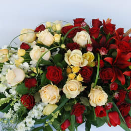 Red and cream roses with red lilies in a large floral spray
