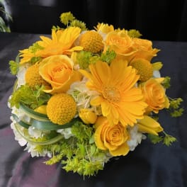 Yellow roses and gerbera daisies in a low bouquet with white flowers
