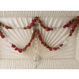 White draped casket with red rose garland