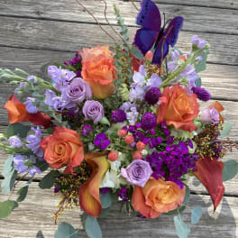 Bouquet of orange and lavender flowers with a purple butterfly pick