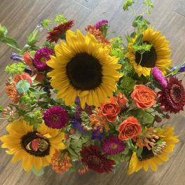 Mixed bouquet with sunflowers, orange roses, and bright accent flowers