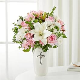Pink and white floral arrangement in a white vase with a cross emblem