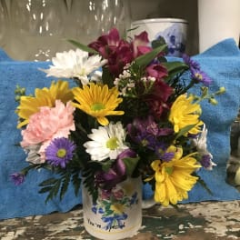 Mixed bouquet of daisies and alstroemeria in a decorated mug