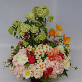Large mixed floral arrangement with pale green blooms, pink roses, and white flowers