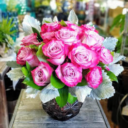 Pink roses arranged in a dark faceted vase with silver foliage