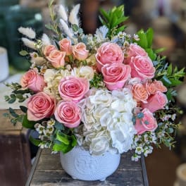 Pink roses and white hydrangeas arranged in a white ceramic vase