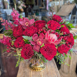 Red rose bouquet with pink orchids in a gold vase