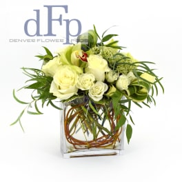 White roses and green orchids in a square glass vase