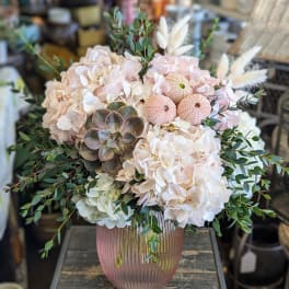 Blush hydrangeas and succulents in a pink ribbed vase with airy greenery