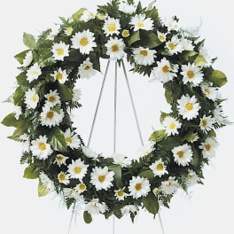 Standing wreath of white daisies with yellow centers on a metal easel