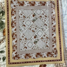 Packaged quilt with a floral patchwork pattern in cream and brown