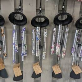 Hanging silver wind chimes with floral accents on a wooden display