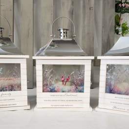Three white lanterns with printed memorial scenes and quotes