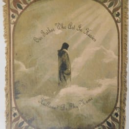 Decorative wall hanging with a robed figure in clouds and cursive text