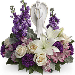Purple and white floral arrangement with an angel figurine