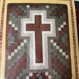 Framed quilt with a large cross pattern in red, white, and dark tones