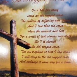 A printed memorial poem with a wooden cross against a cloudy sky