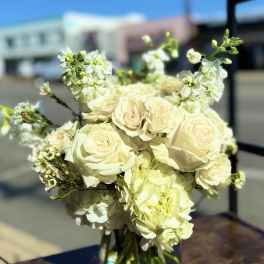Bouquet of cream roses and white blossoms in a clear glass vase