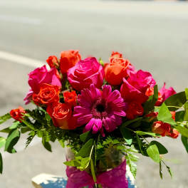 Pink and orange roses with a magenta daisy in a glass vase