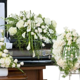 White funeral casket spray with roses, calla lilies, and hydrangeas