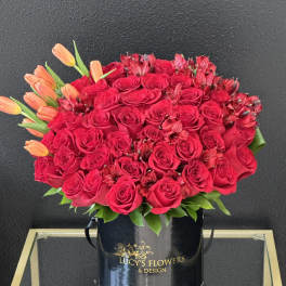 Red rose bouquet with orange tulips in a black hatbox