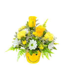 Yellow and white flower arrangement in a smiley-face pot