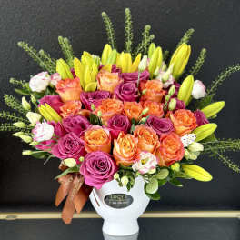 Bouquet of pink and orange roses with yellow lilies in a white vase