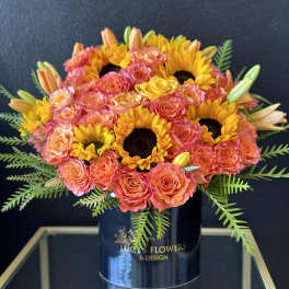 Bouquet of coral roses and yellow sunflowers in a black vase