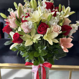 Bouquet of red and blush roses with pale lilies in a glass vase