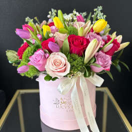 Mixed bouquet of roses and tulips in a pink hatbox
