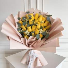 Bouquet of yellow roses wrapped in blush pink paper