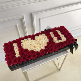 Heart-shaped box of red and cream roses on a table